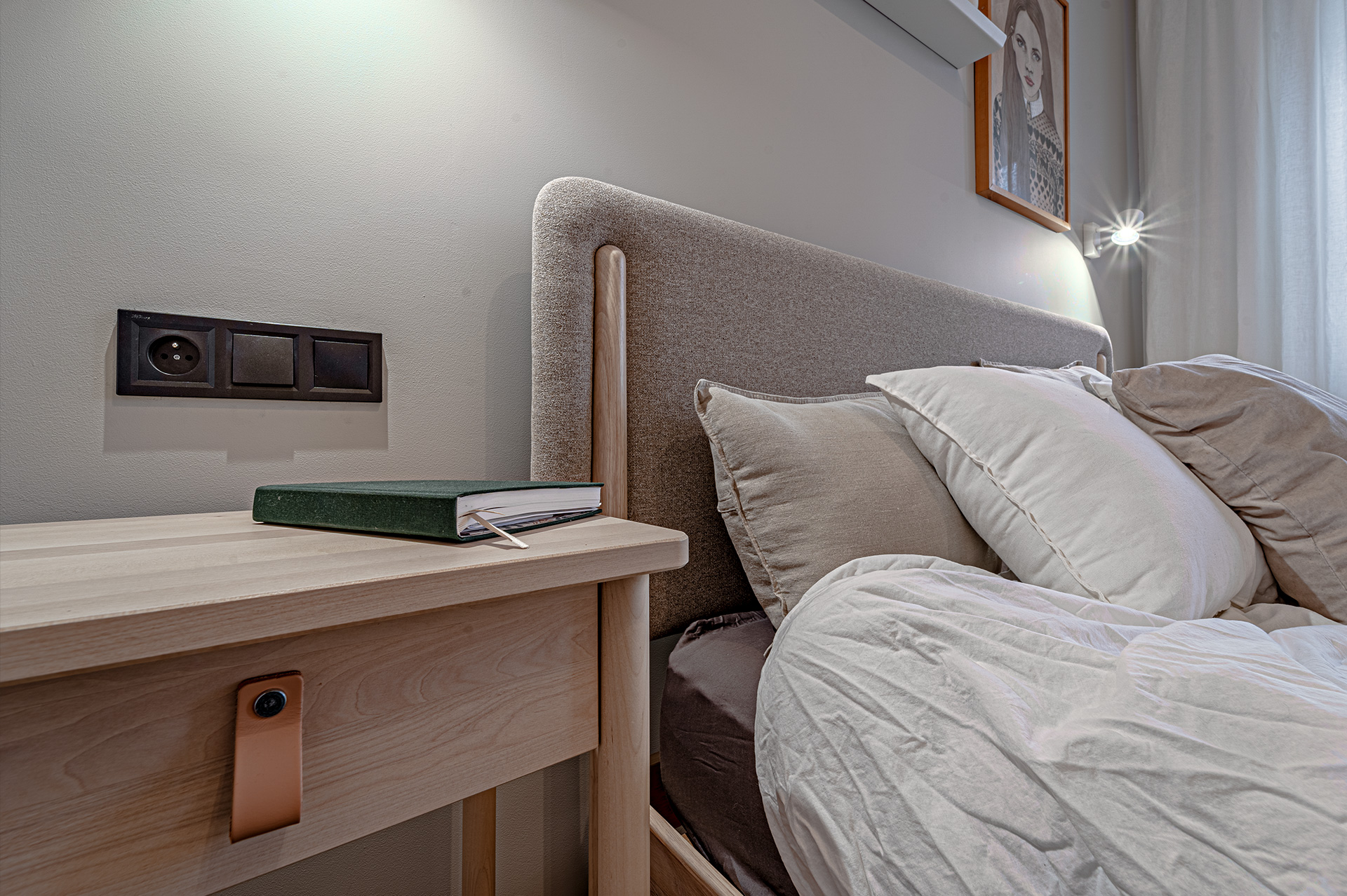 Łóżko z tapicerowanym zagłówkiem oraz drewniane stoliki nocne po obu stronach dodają wnętrzu ciepła i przytulności.