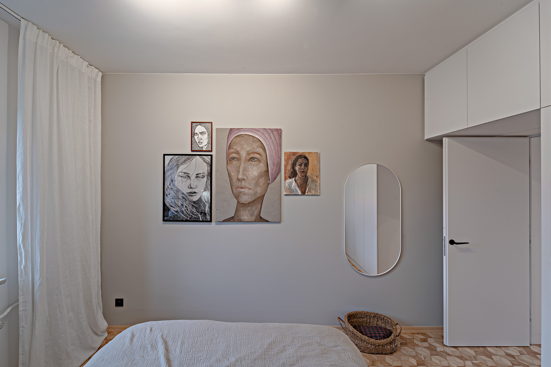 Pieczołowicie skomponowana kolekcja kobiecych portretów na ścianie naprzeciw łóżka.